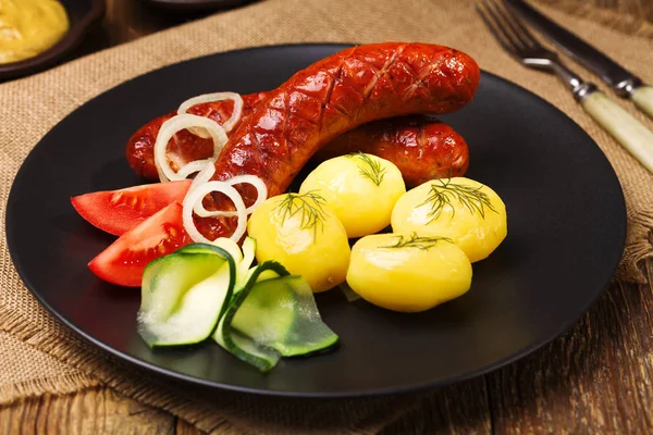 Soğan ile bir tavada ızgara sosis, haşlanmış patates ile servis — Stok fotoğraf