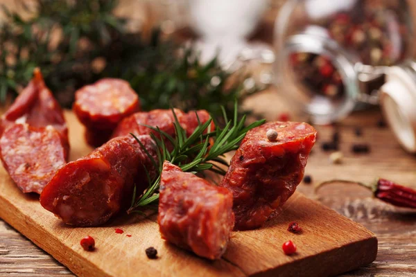 Delicious smoked sausage, sliced on a wooden board with spices. — Stock Photo, Image