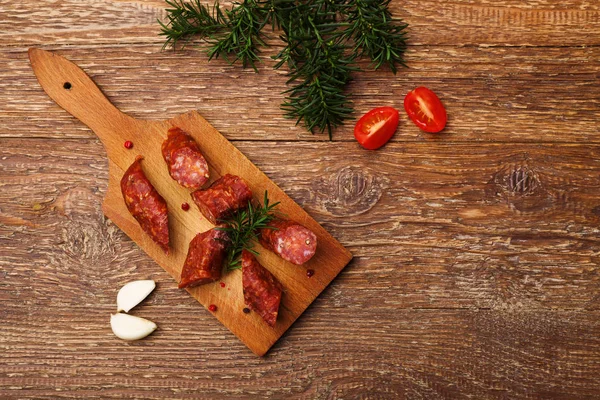 Délicieuse saucisse fumée, tranchée sur une planche de bois aux épices . — Photo