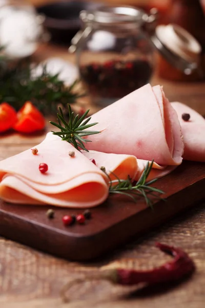 Delicious cooked ham on a wooden board with spices. — Stock Photo, Image