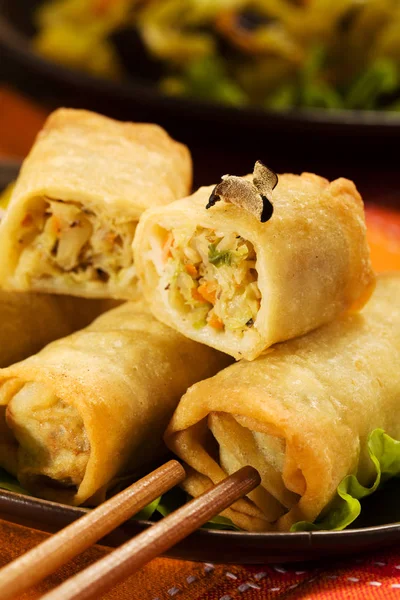 Portion baked spring rolls with vegetables and rice on a plate.