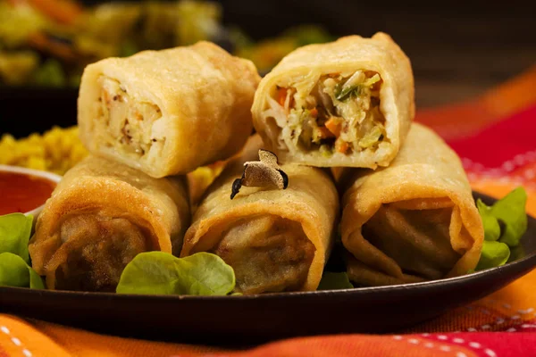 Portion baked spring rolls with vegetables and rice on a plate.