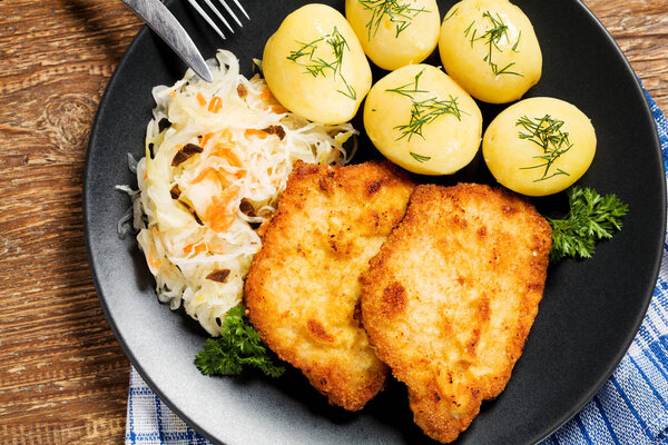 Fried pork chop in breadcrumbs, served with boiled potatoes and 