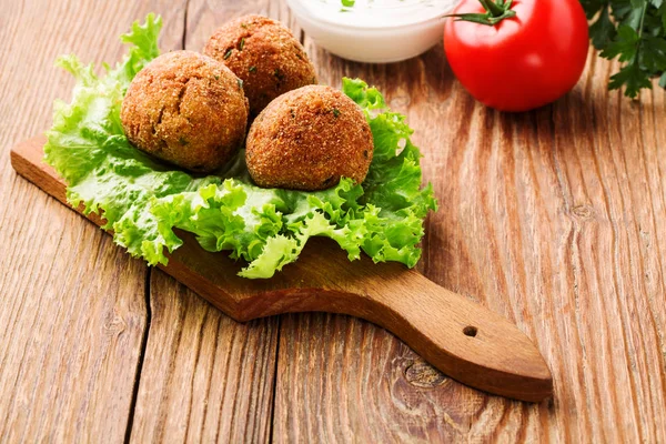 Bolinhas de falafel de grão de bico em uma mesa de madeira com legumes — Fotografia de Stock