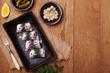 Sirke de haddelenmiş ringa, soğan ve turşu ile servis. 