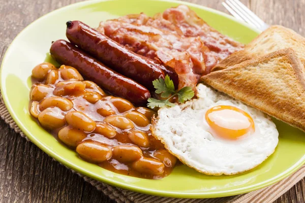 Повний англійський сніданок з беконом, сосискою, смаженим яйцем, запеченою квасолею — стокове фото