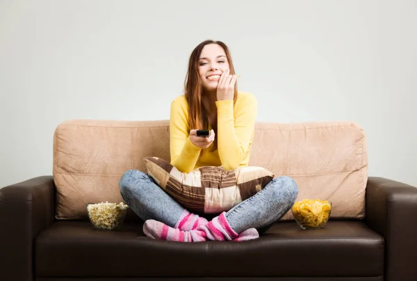 Giovane donna trascorre il suo tempo libero guardando la TV sul divano a hom — Foto Stock