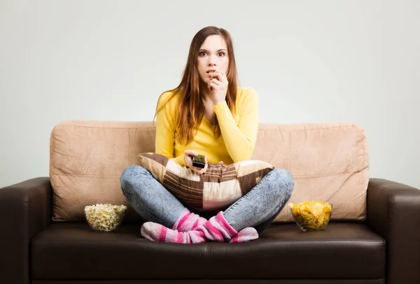 Mujer joven pasa su tiempo libre viendo la televisión en el sofá en hom —  Fotos de Stock