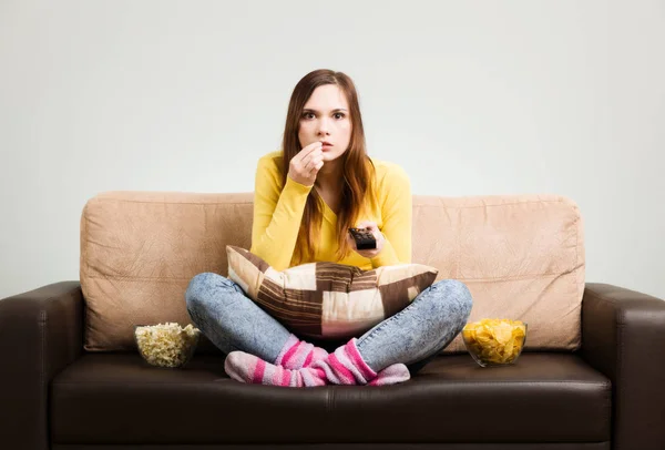 Mujer joven pasa su tiempo libre viendo la televisión en el sofá en hom —  Fotos de Stock
