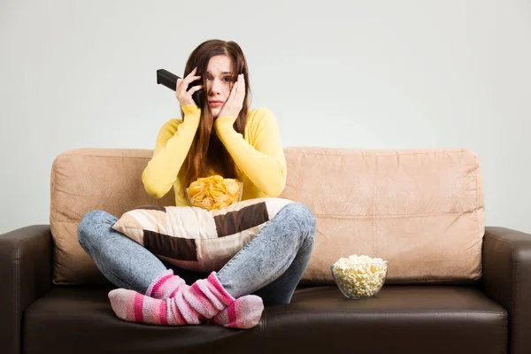 Молодая женщина проводит свое свободное время, смотря телевизор на диване в доме — стоковое фото