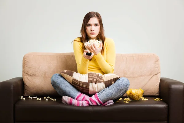 Mujer joven pasa su tiempo libre viendo la televisión en el sofá en hom —  Fotos de Stock