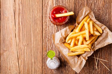 Tahta arka planda ketçaplı taze kızarmış patates kızartması.