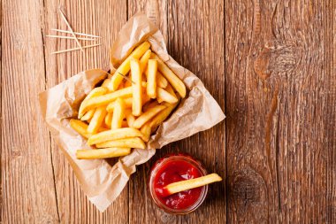 Tahta arka planda ketçaplı taze kızarmış patates kızartması.