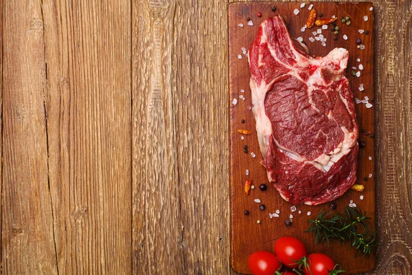 Steak de boeuf cru frais sur une planche de bois — Photo