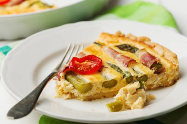 Kuşkonmazlı tart ve beyaz ahşap arka planda domates..