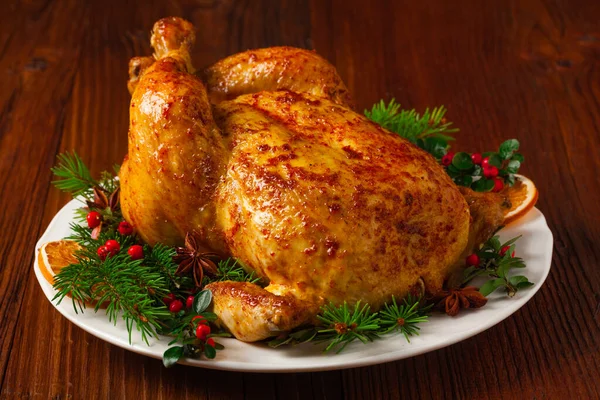 Roasted whole chicken with Christmas decoration. Wooden background. Front view.