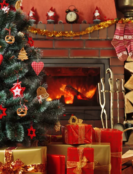 クリスマスプレゼントクリスマスツリーの下の轟音暖炉の背景に — ストック写真