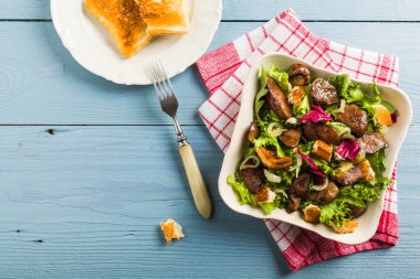 Kızarmış tavuk ciğeri ve tost ile sıcak salata. Üst görünüm.