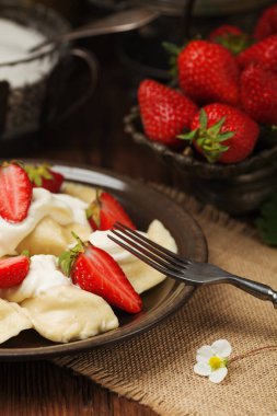 Krem şanti ve şekerle servis edilen taze çilekli lezzetli hamur tatlısı. Arkaplan olarak koyu tahta tablo.