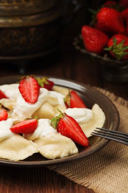 Krem şanti ve şekerle servis edilen taze çilekli lezzetli hamur tatlısı. Arkaplan olarak koyu tahta tablo.