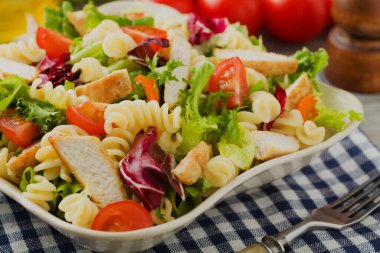 Yeşil marul, domates ve kızarmış tavuklu lezzetli makarna salatası..
