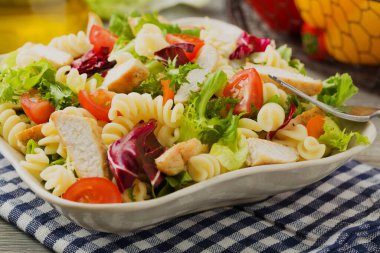 Yeşil marul, domates ve kızarmış tavuklu lezzetli makarna salatası..