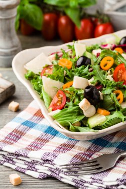 Siyah zeytinli ve parmesanlı taze sebzeli İtalyan salatası. Antika manzara.
