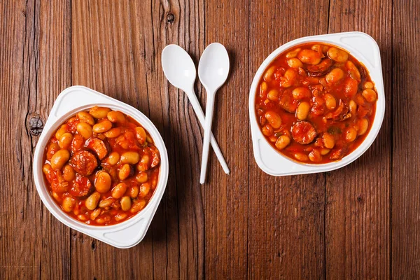Baked beans in tomato sauce served in plastic cups. Top view.