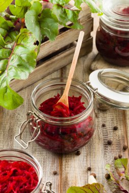 Kavanozda marine edilmiş rendelenmiş pancar kökü. Ahşap arkaplan.