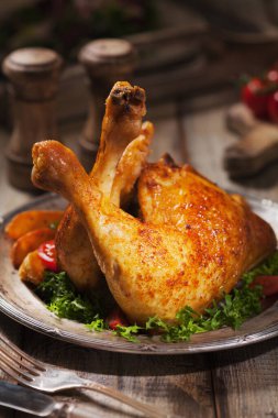 Kızarmış tavuk budu, kızarmış patates ve sebzeyle servis edilir. Antika bir manzara. Eski tabaklar, çatal bıçak takımı ve masalar.. 