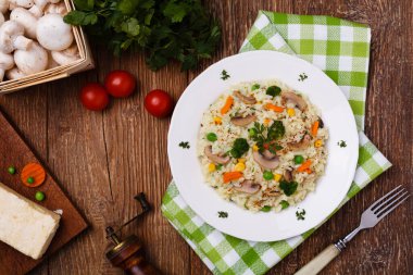 Beyaz tabakta servis edilen mantarlı ve sebzeli klasik risotto..