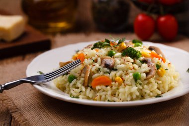 Beyaz tabakta servis edilen mantarlı ve sebzeli klasik risotto..