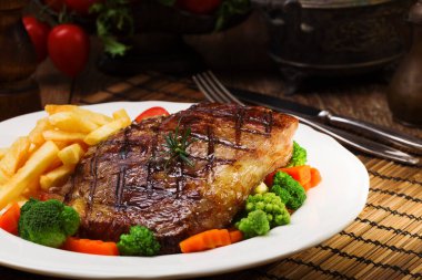 Kızarmış biftek, patates kızartması ve sebzeyle servis edilir..