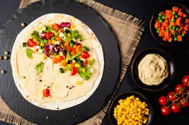 Sebzeli tortilla ve nohutlu humus. Üst Manzara. Siyah arkaplan. 