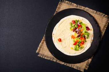Sebzeli tortilla ve nohutlu humus. Üst Manzara. Siyah arkaplan. 