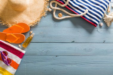 Yaz tatili teması deniz kabukları, çanta, şapka, güneş gözlüğü ve fotokopi alanı olan mavi ahşap arka plan. Üst görünüm.