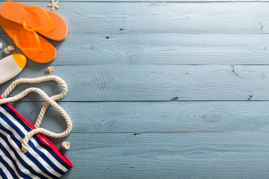 Yaz tatili teması deniz kabukları, çanta, şapka, güneş gözlüğü ve fotokopi alanı olan mavi ahşap arka plan. Üst görünüm.