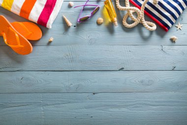 Yaz tatili teması deniz kabukları, çanta, şapka, güneş gözlüğü ve fotokopi alanı olan mavi ahşap arka plan. Üst görünüm.