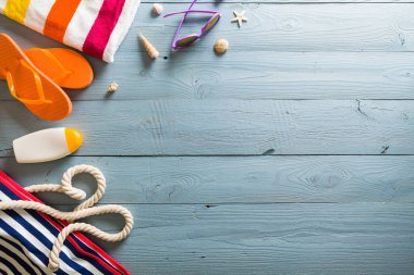 Yaz tatili teması deniz kabukları, çanta, şapka, güneş gözlüğü ve fotokopi alanı olan mavi ahşap arka plan. Üst görünüm.