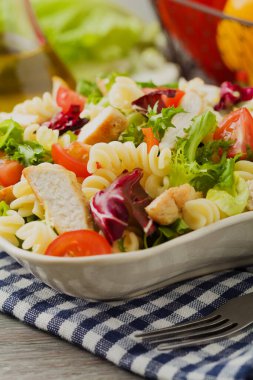 Yeşil marul, domates ve kızarmış tavuklu lezzetli makarna salatası..