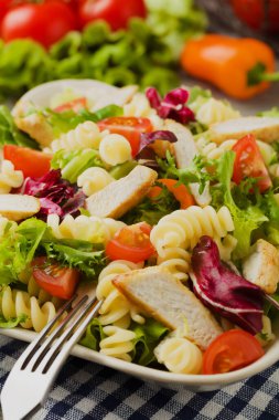 Yeşil marul, domates ve kızarmış tavuklu lezzetli makarna salatası..
