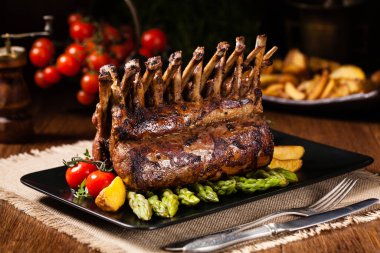 Fırında kuzu fileto, kuşkonmazla servis edilir. Koyu arkaplan.