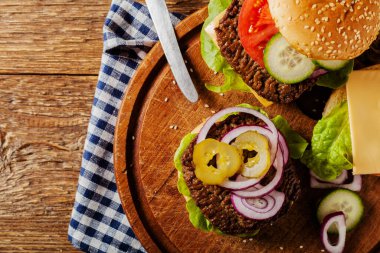 Ev yapımı, peynirli ve sebzeli sığır burger. Üst görünüm.