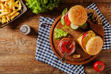 Ev yapımı, peynirli ve sebzeli sığır burger. Patates kızartmasıyla servis edilmiş. Üst görünüm.