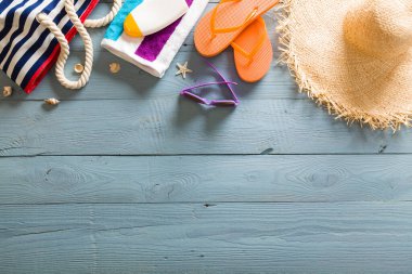 Yaz tatili teması deniz kabukları, çanta, şapka, güneş gözlüğü ve fotokopi alanı olan mavi ahşap arka plan. Üst görünüm.