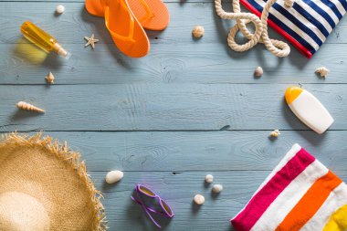 Yaz tatili teması deniz kabukları, çanta, şapka, güneş gözlüğü ve fotokopi alanı olan mavi ahşap arka plan. Üst görünüm.