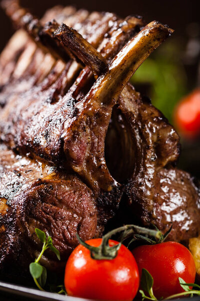 Запеченный ягненок, подается со спаржей. Темный фон.