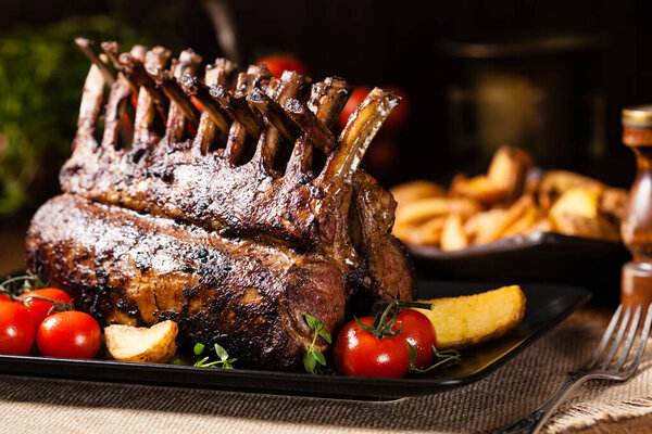 Запеченный ягненок, подается со спаржей. Темный фон.