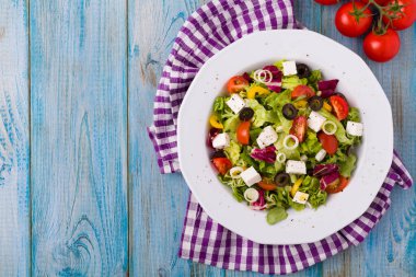 Tabakta taze Yunan salatası. Mavi ahşap tahta. Üst görünüm.