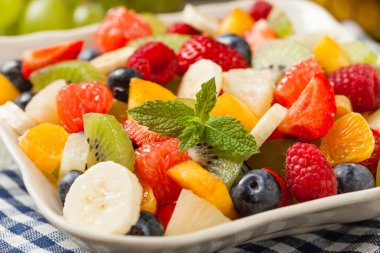 Taze meyveli lezzetli meyve salatası. Arkadaki tahta, gri masa. Ön görünüm.